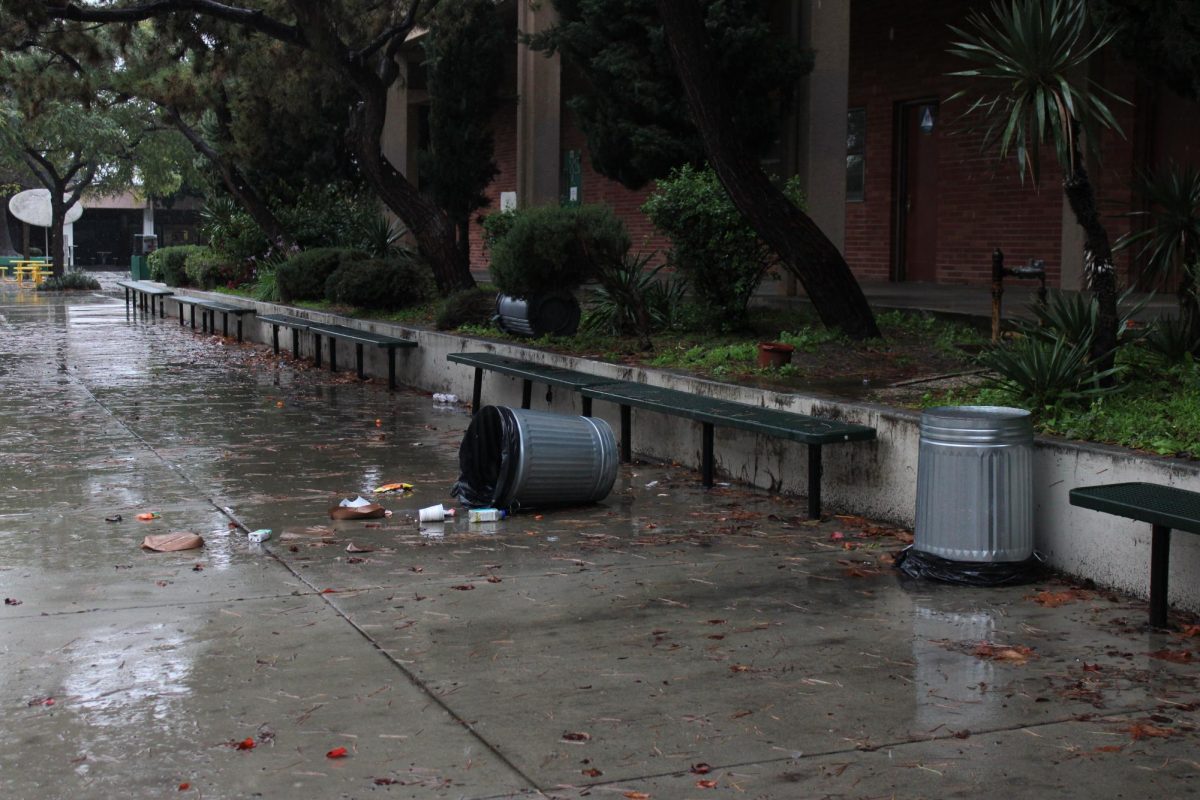 A trashcan is toppled over from harsh wind.
