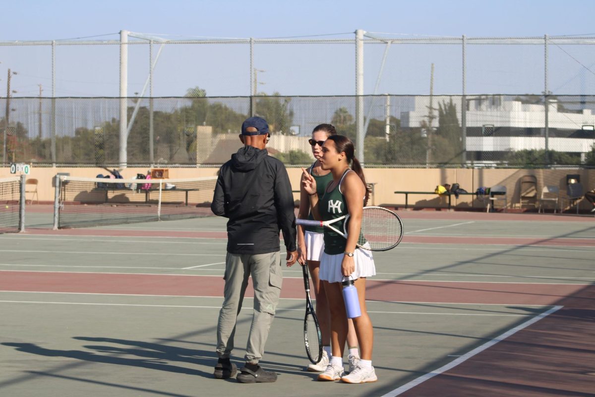 Tennis players have a pep talk with Coach Gaiter.