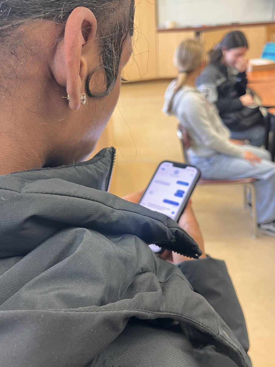 A student is on their phone despite the new phone ban.