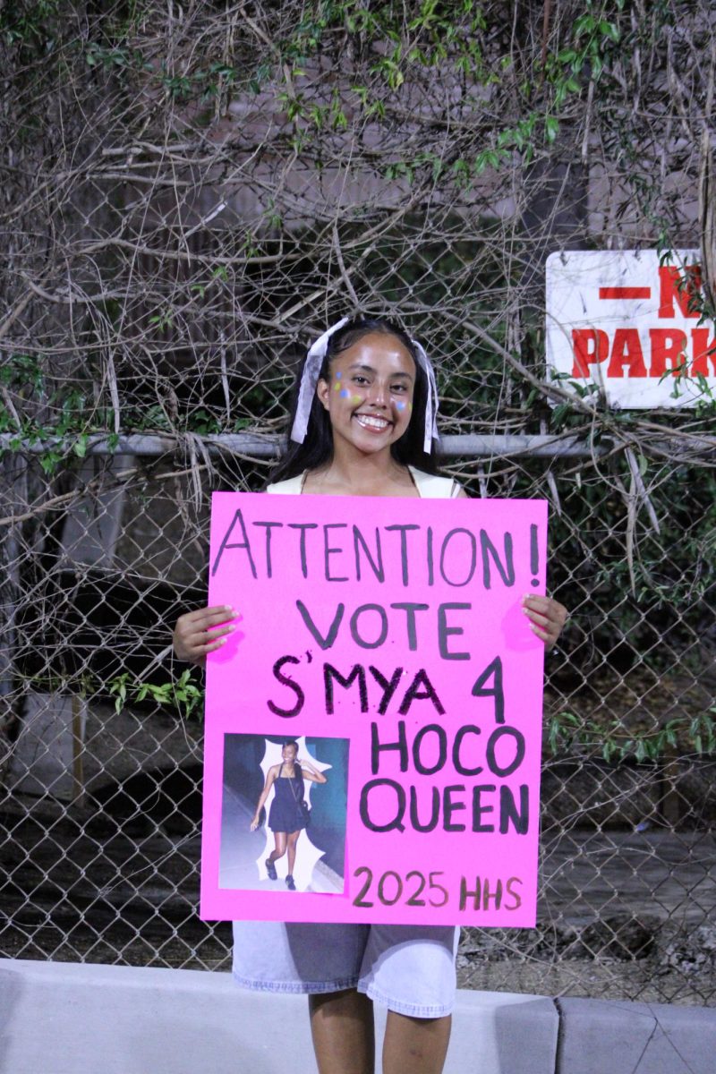 SAS Sophomore Leslie Jimenez poses for photo before walking in the Homecoming parade. She is holding a sign to help campaign for Homecoming queen S'mya Martin. 