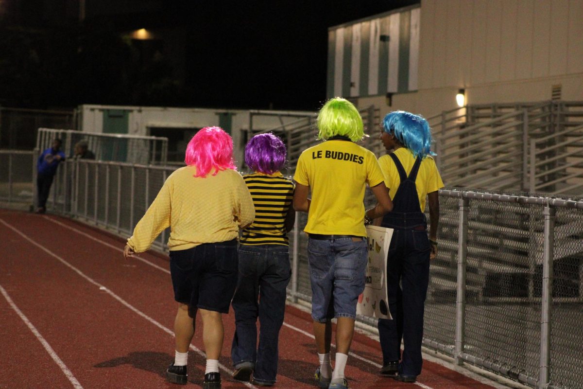 Tyron Fernando (green wig) and friends walk to the Homecoming game parade. The sign in Tyron's hand is to help his campaign for Homecoming prince.