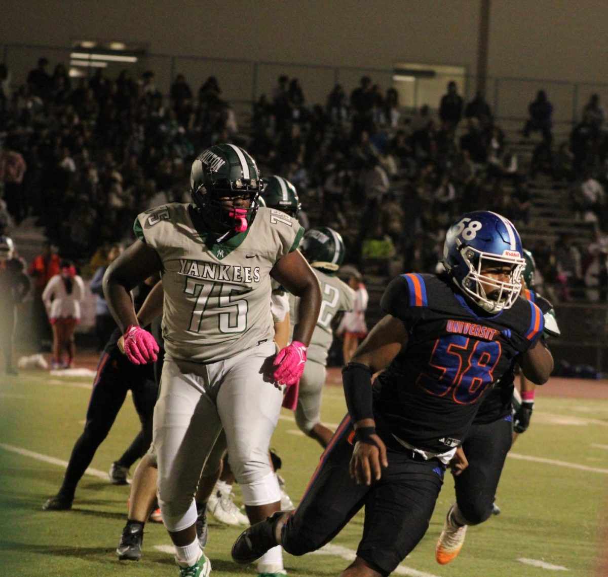 #75 Micah Butler runs towards Uni #58 in the middle of a play. 