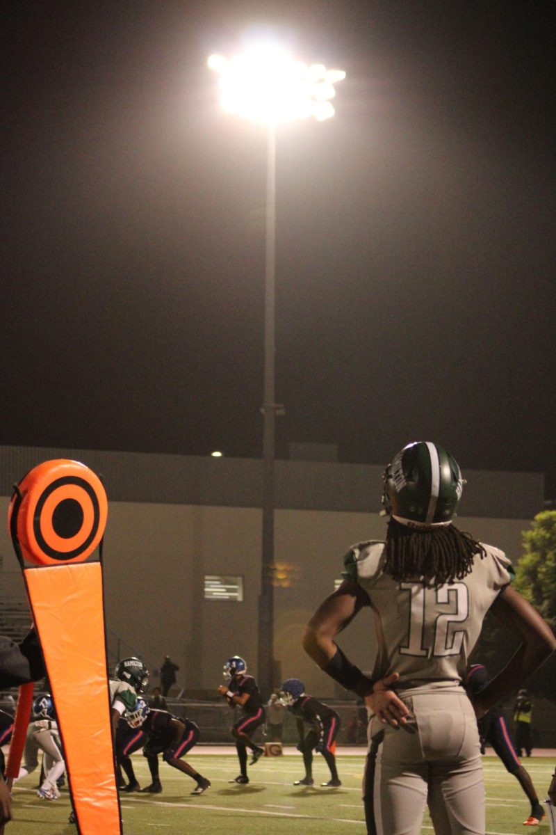 #22 Thaddeus Breaux stands on sidelines during the third quarter. He watches on as a tackle commences. 
