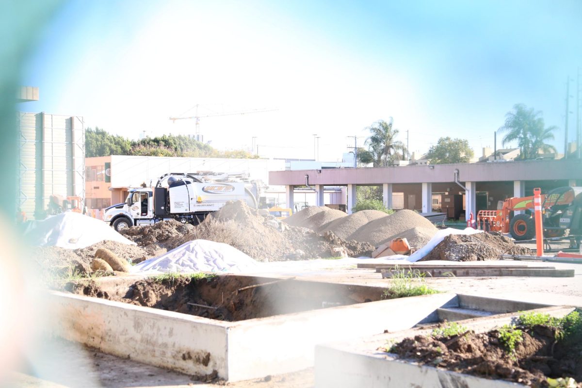 Through the gate, a view of the quad is shown, with mounds of dirt surrounding the area. The stage that was once there is now completely demolished. Other tables and trees were also cut down for remodeling. 