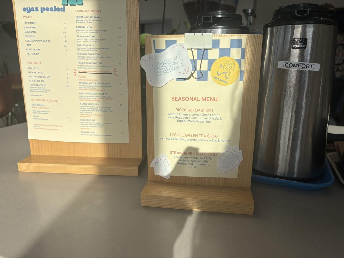 A sign displaying the New Spring menu for the 2026 season is placed at the front counter of the coffee shop, highlighting their creative specials. 