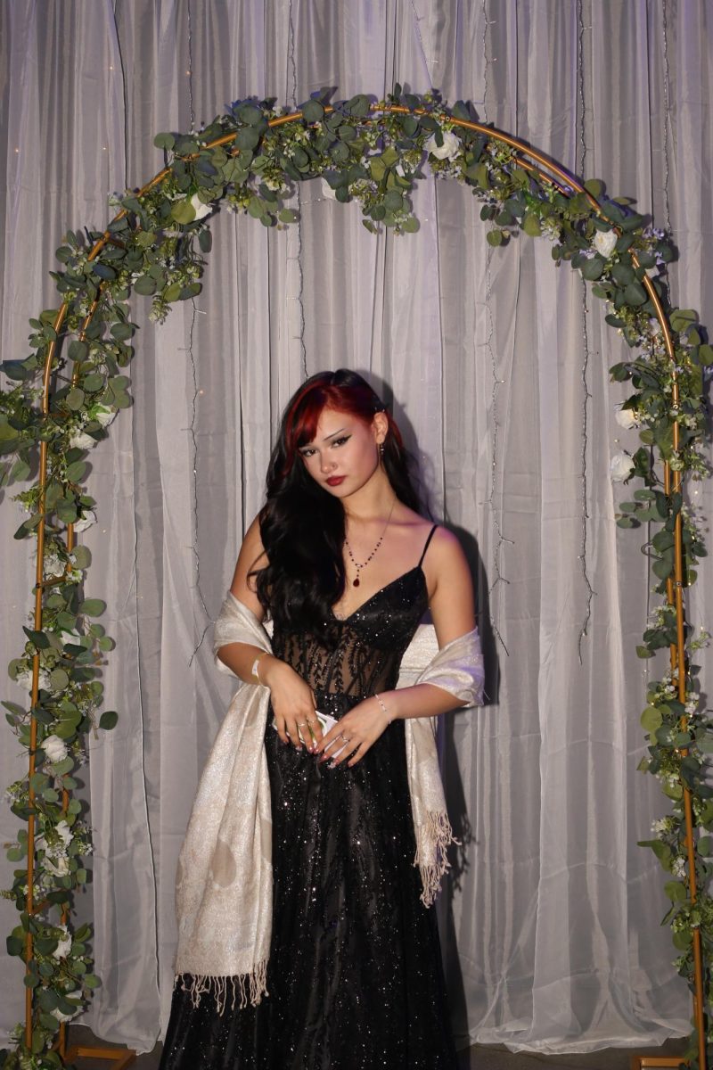 AMPA junior Saya Decker stands underneath a decorative arch with a beautiful black dress. 